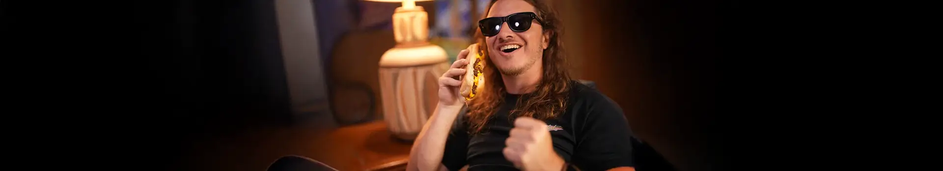 Eric Sollenberger smiling while holding a cheesesteak to his ear like a phone